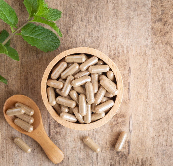 Supplement capsules shown in a bowl on a wooden table
