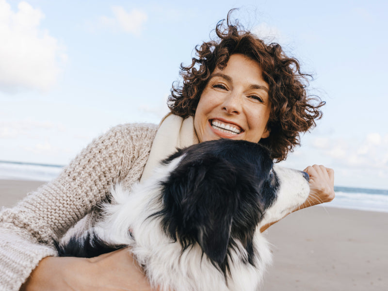 Image of woman playing with dog on the beach